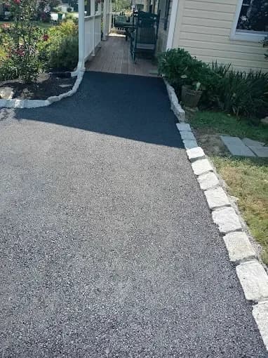 Asphalt walkway with stone block edging leading to a front porch
