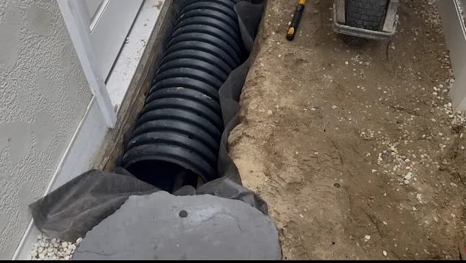 Corrugated drainage pipe in a trench along a foundation wall